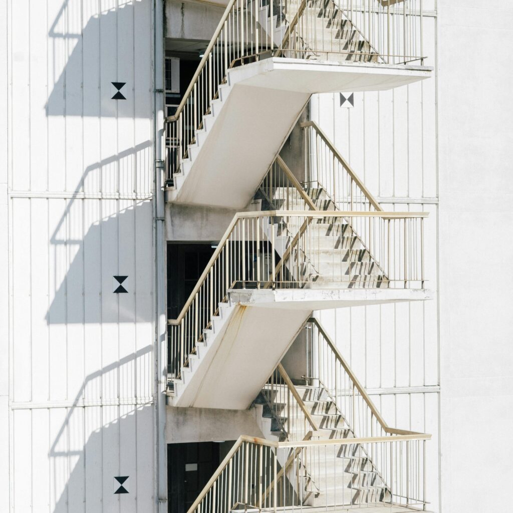High stairway of contemporary stairway with metal railing of white wall of building in sunlight