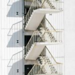High stairway of contemporary stairway with metal railing of white wall of building in sunlight